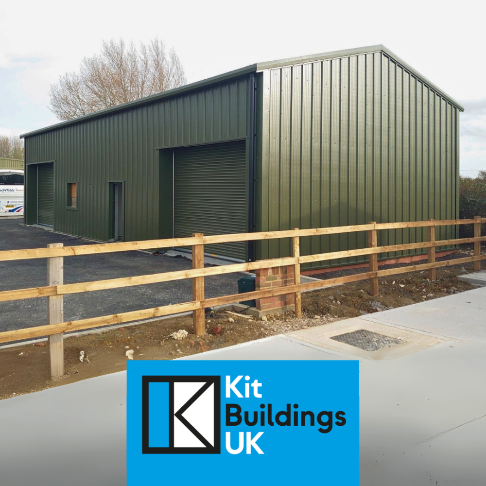 Industrial steel framed building in green, featuring two roller doors and a pedestrian door.